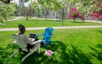 A student works on a laptop outside. 