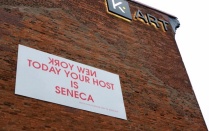K Art Gallery, exterior brick wall with sign reading "New York" in mirrored writing, then "Today your host is Seneca". 