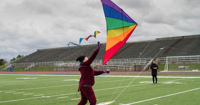 Students from Coalesce flying a rainbow kite on the football field. 