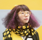 Headshot of Tansy Xiao, wearing a black and yellow polka dot scarf. 