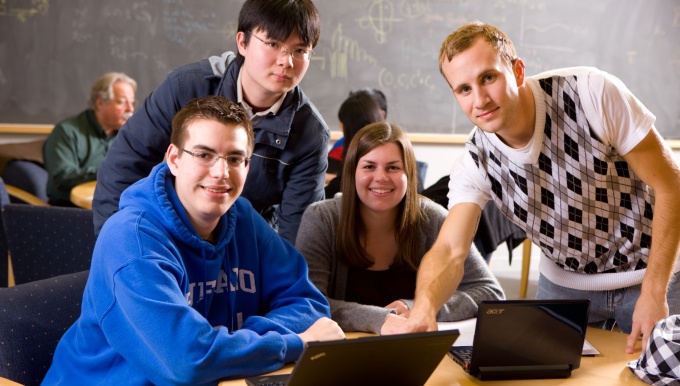 Undergraduate students gathered around a computer. 