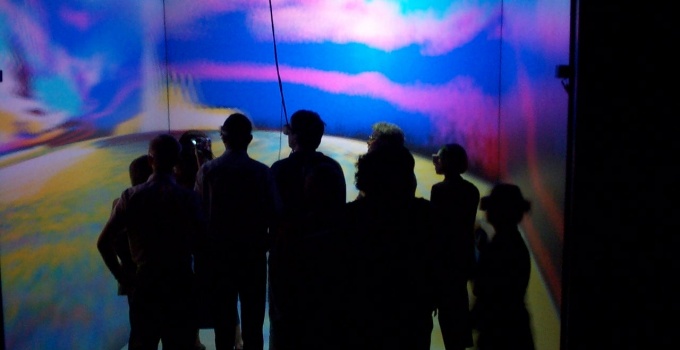 students in silhouette in front of colorful wall projection. 