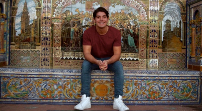 Student sitting in front of Spanish mosaic. 
