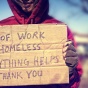 Person holding cardboard sign asking for help due to homelessness. 