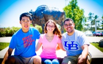 Three students sitting in front of the Buffalo statue. 