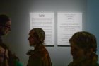 Visitors pass by a description of the exhibition.