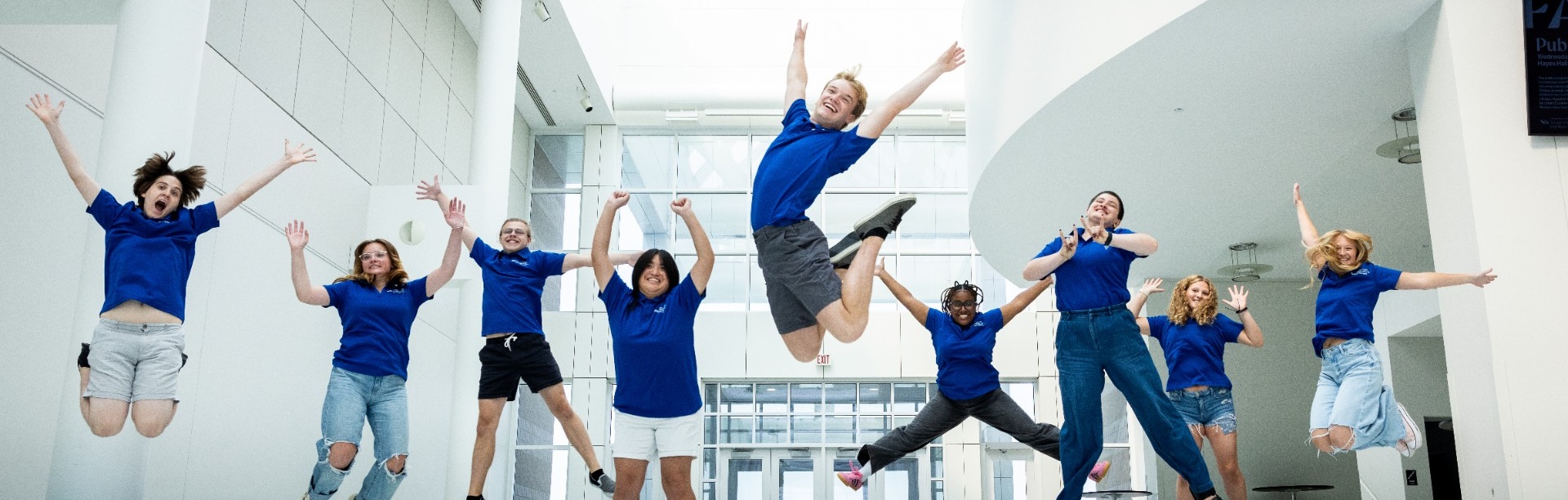 Students jump in the air and smile. 