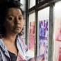 Crystal Z Campbell standing by window with colored fabrics. 