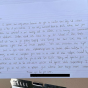 Handwritten letter on lined paper, resting on a clipboard held by hand. 
