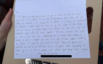 Handwritten letter on lined paper, resting on a clipboard held by hand. 