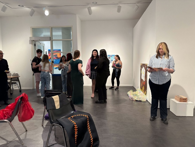 Zoom image: Guests visiting the BFA Senior Thesis group exhibition "Supreme", April 29th, 2024, in the Department of Art Lower Gallery, room B45 of the Center for the Arts.