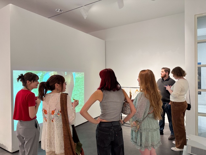 Zoom image: Guests visiting the BFA Senior Thesis group exhibition "Supreme", April 29th, 2024, in the Department of Art Lower Gallery, room B45 of the Center for the Arts.