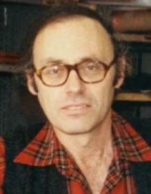 Harvey Breverman headshot with red flannel shirt and large brown frame glasses/. 