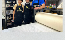 Three people wearing aprons stand in front of a printing press. "MIRABO Rachel Shelton, Mizin Shin, Bob Fleming". 