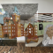 "The Quality of Mercy", artwork assembled installation, made of, acrylic, pen on Dura-Lar polymer film, depicting a tall brown stone building, a woman with her hands clutching the dies of her face, and another woman peaking through the slots of miniblinds, with other geometric elements layered in front of and behind this imagery. In an art gallery with white wall and hardwood floors. 