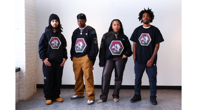 Zoom image: Four people wearing black apparel featuring the Sabres Black History celebration crest designed by George Hughes.