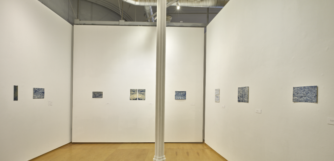 Zoom image: white wall art gallery with shades of blue small artworks hung around the room