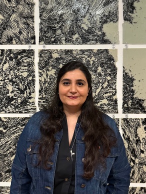 Woman stands in front of art panels made on glass rectangles with wave patterns. 