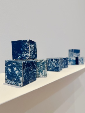 Blue and white paper cubes sitting on a white shelf. 