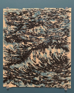 blue and black glass shards fused on a cream glass panel, hanging on a teal wall. 