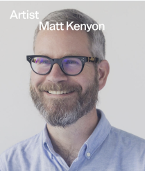 Headshot of a bearded man wearing dark blue framed glasses and a light blue shirt. 