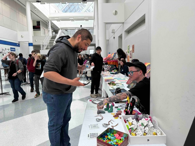 Zoom image: MFA Candidate H. Boone selling their 3D-printed wares in the Student Art Sale 