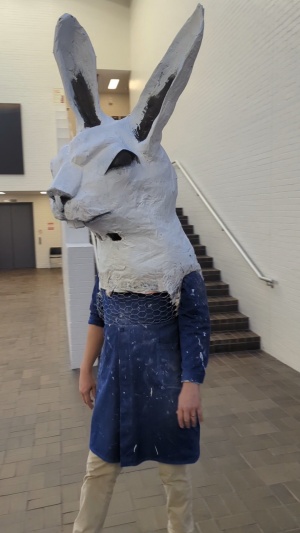 Sculpture "Bunny Bunny" by artist Frederick Wright Jones, dpeicting a large white rabbit headbeing worn over the head and shoulders of a person. 