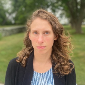 Zoom image: Julia Lillie headshot wearing a white and blue chevron shirt with a black cardigan over top.