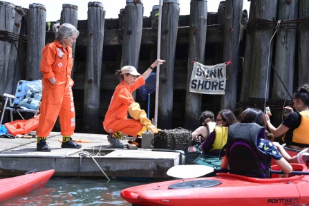 Zoom image: Sunk Shore tour guides Clarinda Mac Low and Carolyn Hall greeting travelers on Flushing Creek as part of Cody Ann Herrmann&rsquo;s project &ldquo;Brownfield Boating&rdquo; in Queens, New York City. Photo by Julian Louis. 2021. 