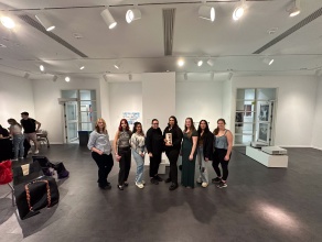 Zoom image: Spring 2024, during the exhibition &quot;Supreme: BFA Senior Thesis&quot; Wide lens group portrait of the BFA Senior cohort, with P rofessor Ilona Gaynor. Facing the long wall of the gallery on which both entrances are located, with the mobile wall abutting the 22'6&quot; recessed wall, perpendicularly.  Image Credit: Whitney Kehl 