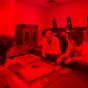 Zoom image: three people around water baths and trays in a photoigraphy daerk room