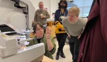Josie Freeman demonstrates to a group of onlookers how to place the small lower bobbin into the embroidery machine. 
