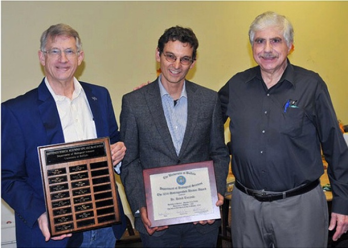 Photo caption: Dr. David Toczyski (center) delivered the Spring 2018 Distinguished Alumni Seminar. After the seminar, Drs. Stephen Free (left) and Ronald Berezney (far right) presented Dr. Toczyski with the UB Department of Biological Sciences Distinguished Alumni Award. Photograph by James Stamos. 
