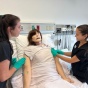 UB SLP Students Megan Orrange and Alli Barsi prepare an airway mannikin for a speaking valve trial in a simulated hospital room. 