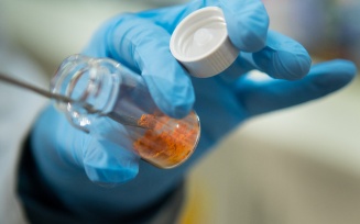 Researcher using a scoopula to transfer a sample from a bottle. 