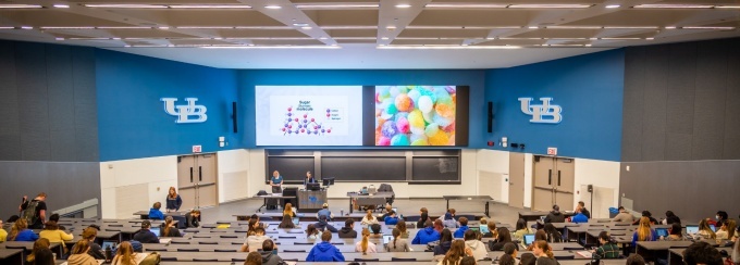 Speaker presenting in University at Buffalo lecture hall. 