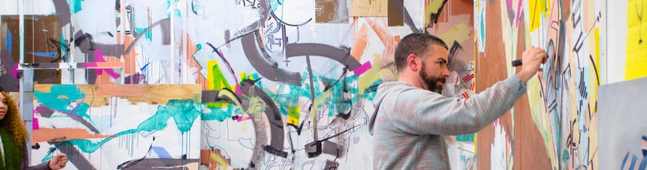 Student in art studio working on a mural. 
