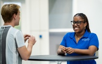 2 students speaking at a table. 