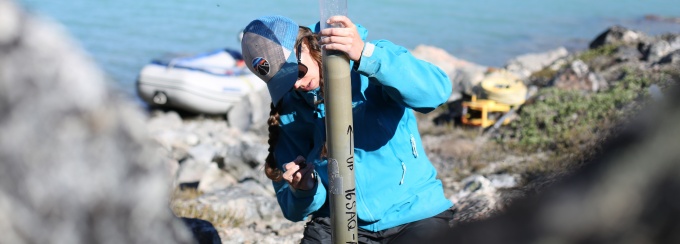 A student takes measurements out in the field. 