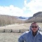 Da Lin standing in front of a landscape with trees and small mountains behind it. 