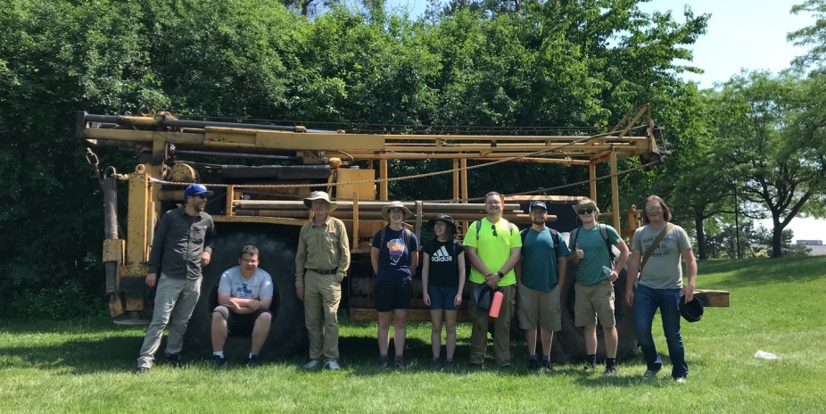 The entire Field Camp of students and faculty stand in front of the drill rig.