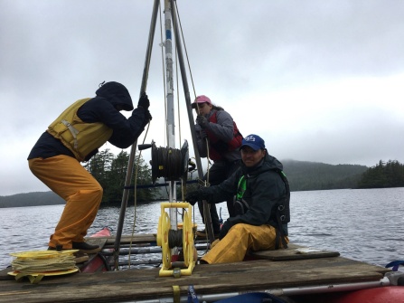 two students and a professor on a research boat on a lake. 