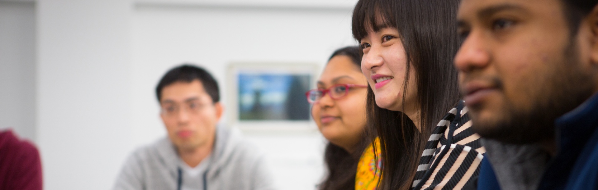 Four economics students are sitting at a table in a classroom.