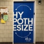 Elevator doors with text that reads "HYPOTHESIZE" on a blue background. 