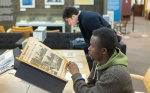 Zoom image: Students in Crystal Campbell’s media study class visit the Libraries Poetry Collection in Capen Hall in March 2024. Materials they interacted with included The Spectrum newspapers, university flags and banners, as well as other things. Photographer: Douglas Levere