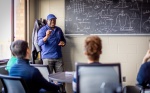 Zoom image: Herbert Fotso, with physics teaches in a graduate study meeting in Fronczak Hall in February 2024. Photographer: Douglas Levere
