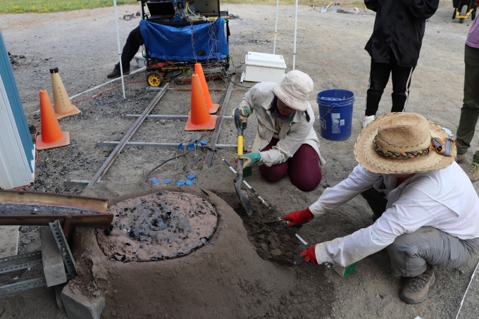 Two people excavating sediment a lava pour. 