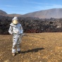 Student in safety equipment near lava flow. 