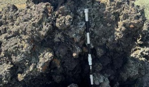 A small (<3m long axis) rafted scoria cone sitting atop a solidified effusive basaltic flow. Inset image is of the spatter texture used to identify rafted scoria cone fragments. Jacob’s staff included for scale. 