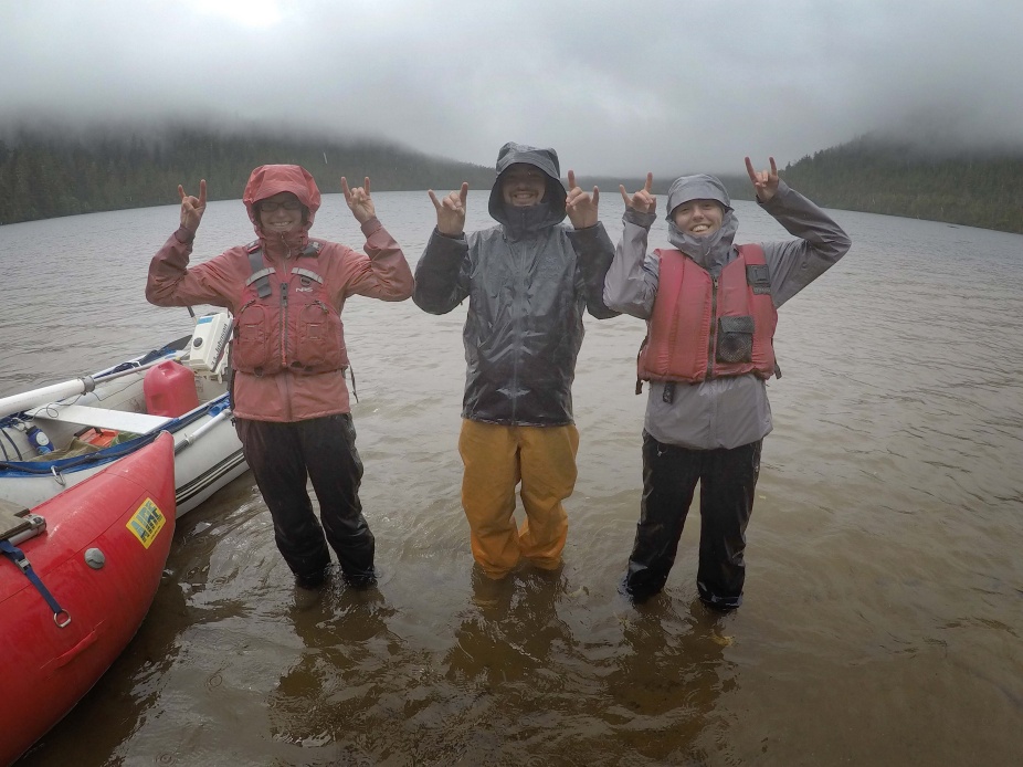 Horns up! From left to right: Department of Geology Assistant Professor Elizabeth Thomas, Caleb Walcott (MS 2021) and Karlee Prince (MS thesis ongoing) at one of Karlee’s study sites on Dall Island, SE Alaska. The team used their sediment coring platform (left side of image) to obtain cores down to 7 m sediment depth at this site; the sediments will be used to reconstruct the climate history of the region. Photo by Jason Briner. 